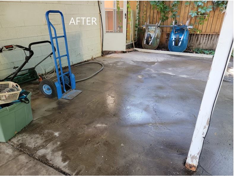 A garage floor with a cleaning machine and a bucket