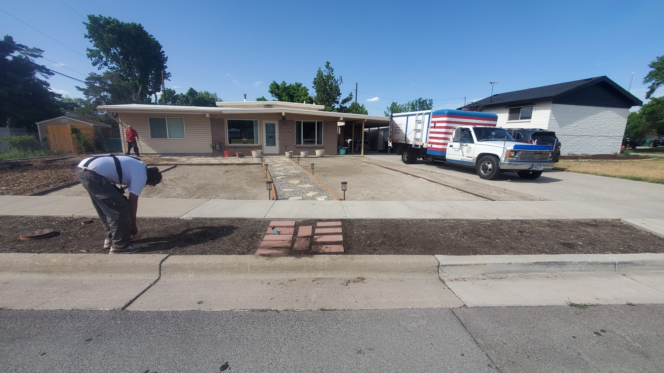 A man is digging dirt in front of a house