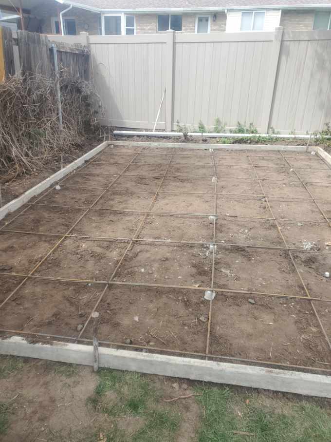 A backyard with a concrete floor and a fence